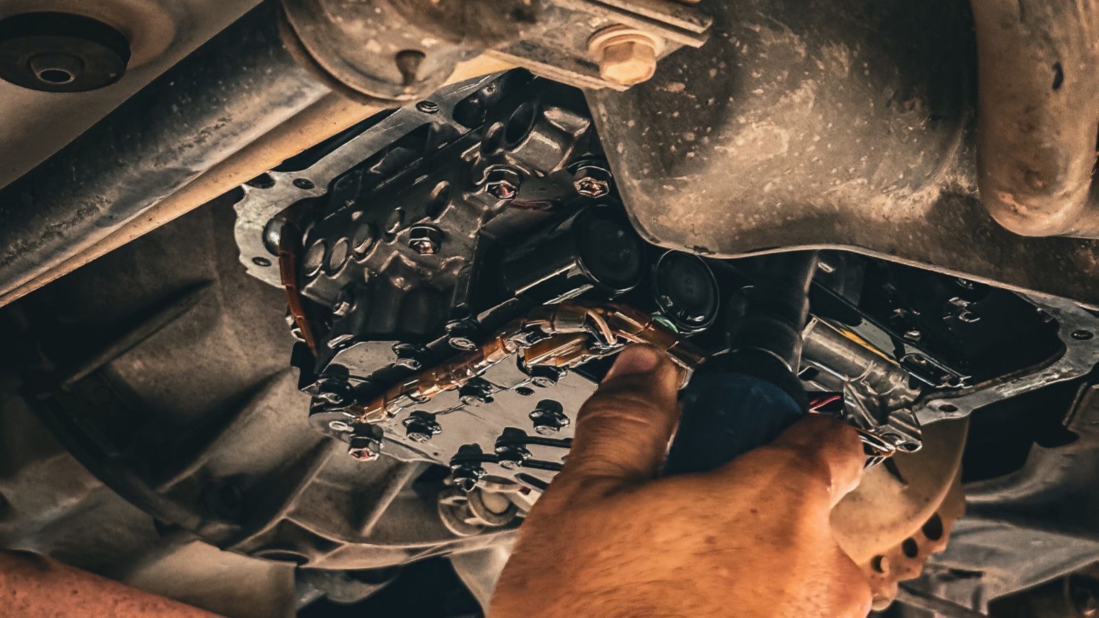 Mechanic inspecting a car clutch and gearbox from underneath